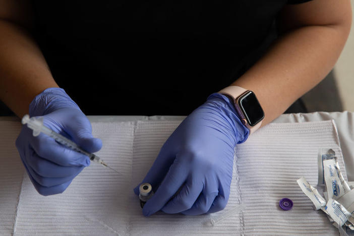 A health care worker fills syringes with doses of the COVID-19 vaccine in August in Southfield, Mich.