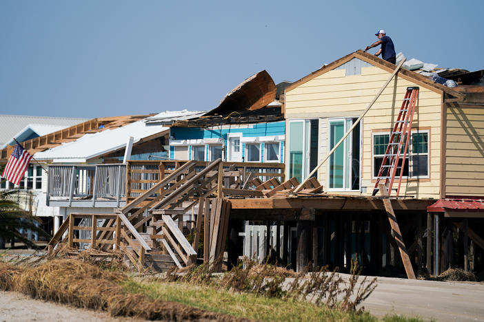 A man works on the roof of a storm-damaged house on Sept. 4 after Hurricane Ida swept through Grand Isle, La. A new poll finds that two-thirds of Americans say if their home is hit by an extreme weather event they'd rather rebuild than relocate.