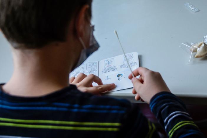 A pupil wearing a face mask reads instructions for a coronavirus rapid test kit at the start of a lesson at an elementary school in Berlin on August 9, 2021.