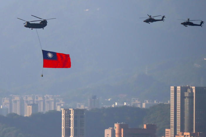 A military helicopter carrying a Taiwanese flag flies near the Taipei 101 building as part of the rehearsal ahead of the Double Ten National Day celebration in New Taipei, Taiwan, on Tuesday.