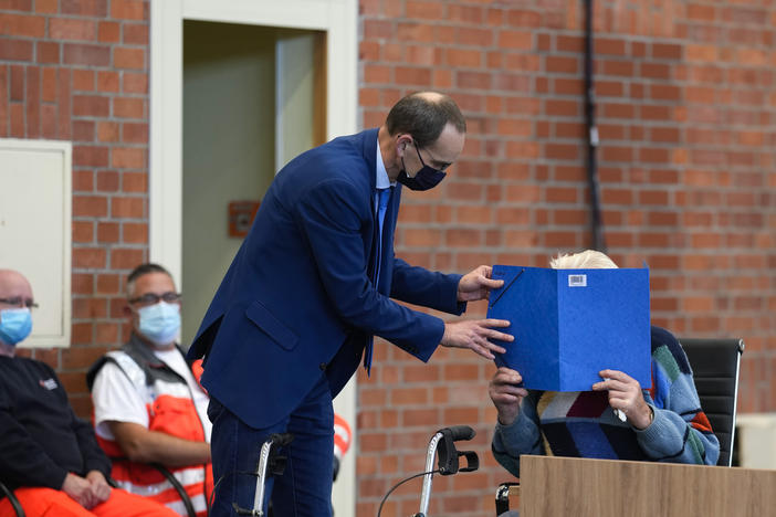 Lawyer Stefan Waterkamp covers the face of accused Josef S. at the court room in Brandenburg, Germany, on Oct. 7, 2021. The 100-year-old man is charged as an accessory to murder on allegations that he served as a guard at the Nazis' Sachsenhausen concentration camp.