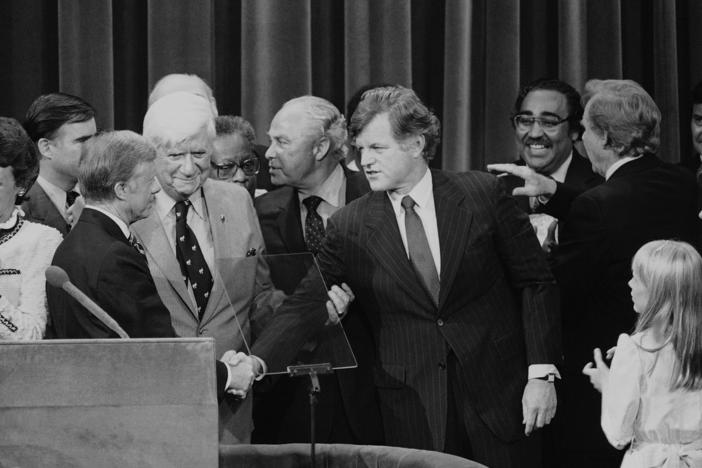 Months after his challenge to the incumbent President Carter had failed, Sen. Edward Kennedy (D-Mass.) makes a belated gesture of unity in the closing moments of the 1980 National Convention.