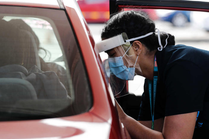 A Health worker administers vaccinations at a pop-up drive-in clinic Monday, Oct. 11, 2021, in Auckland, New Zealand. New Zealand's doctors and teachers are among those who must soon be fully vaccinated against the coronavirus to continue working in their professions, the government announced Monday.