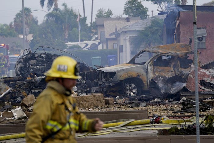 Fire crews work the scene of a small plane crash on Monday in Santee, Calif. At least two people were killed and two others were injured when the plane crashed into the suburban neighborhood, setting two homes ablaze.