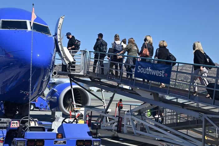 Passengers board a Southwest Airlines airplane at Hollywood Burbank Airport in Burbank, California on October 10, 2021. The airline has continued to cancel or delay hundreds of flights on Monday.