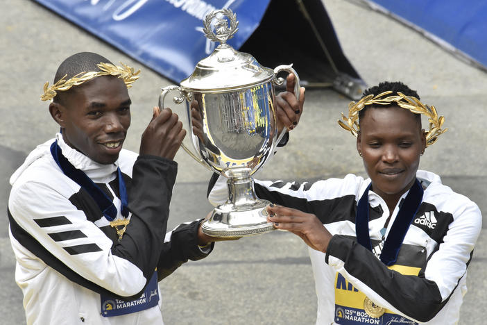 Benson Kipruto (L) and Diana Kipyogei (R) of Kenya hold up the victory trophy after taking first place in the professional men's and women's divisions during the 125th Boston Marathon in Boston, Massachusetts on Monday. The first Boston Marathon since April 2019 strayed from tradition in several ways.