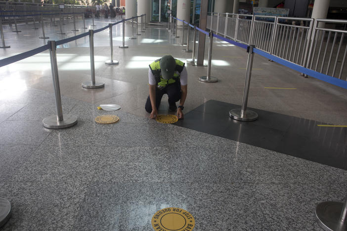 An airport worker marks queue line for the reopening of International Ngurah Rai Airport in Bali, Indonesia, Thursday.