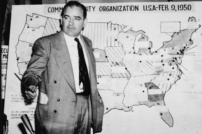 Sen. Joe McCarthy, R-Wis., testifies during hearings in Washington, D.C., on June 9, 1954. McCarthy stands before a map that charts alleged communist activity in the United States.