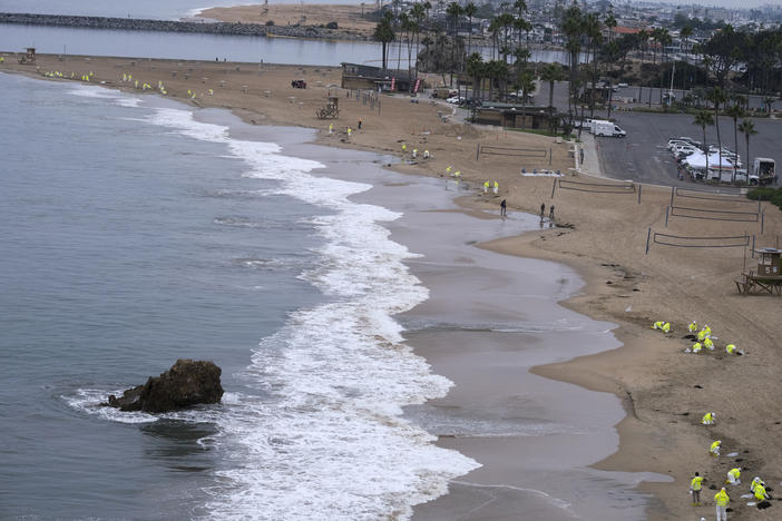 Workers in protective suits clean the contaminated beach in Corona Del Mar on Oct. 7 after an oil spill in Newport Beach, Calif.