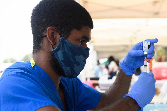 A health care worker prepares a dose of the Moderna COVID-19 vaccine during a clinic held at the Watts Juneteenth Street Fair in the Watts neighborhood of Los Angeles.