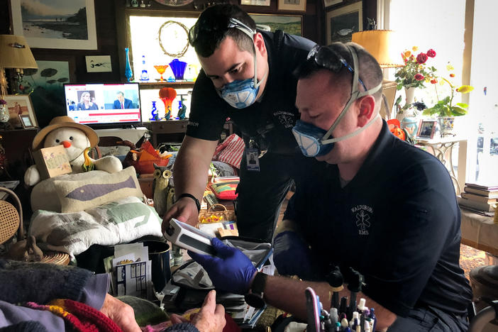 In between answering 911 calls, Jerrad Dinsmore (left) and Kevin LeCaptain perform a wellness check at the home of a woman in her nineties. The ambulance team in the small town of Waldoboro, Maine was already short-staffed. Then a team member quit recently, after the state mandated all health care workers get the COVID-19 vaccine.