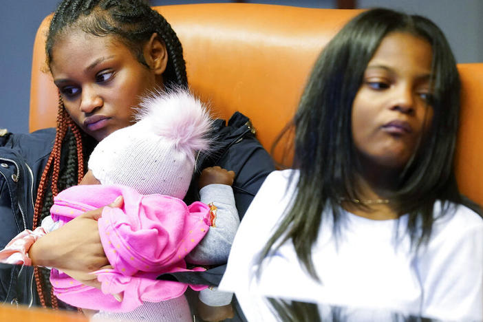 Savannah, left, holds her daughter Chanel, as she sits with her sister Telia, as they listen to their mother Krystal Archie talking Sept. 23 during an interview with the Associated Press in Chicago. Archie's three children were present when police, on two occasions 11 weeks apart, kicked open her front door and tore apart the cabinets and dressers as they executed a search warrant.