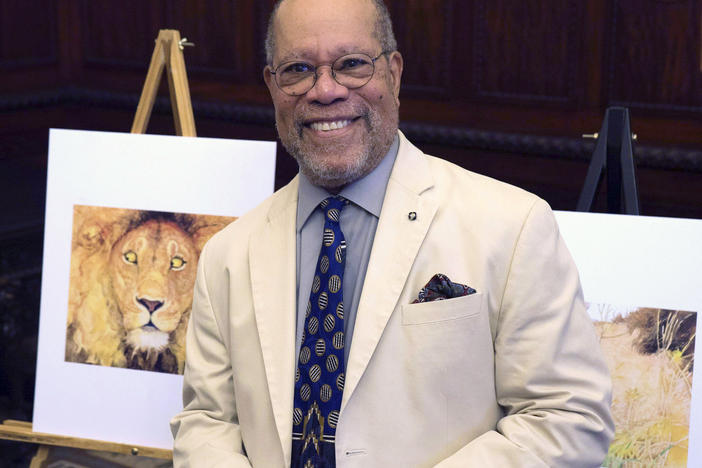 Children's book illustrator Jerry Pinkney poses in front of two of his illustrations in 2016, at the City Hall in Philadelphia.