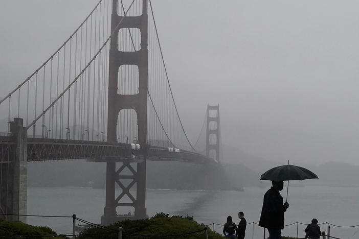 A pedestrian walks with an umbrella near the Golden Gate Bridge in San Francisco during a shower on Wednesday. Strong storms are expected to bring substantial rain to the Western U.S. within the next week.