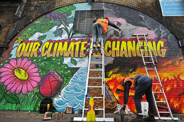 Artists paint a mural on a wall near Scottish Events Centre (SEC) in Glasgow, which will host the U.N. climate summit starting Sunday.