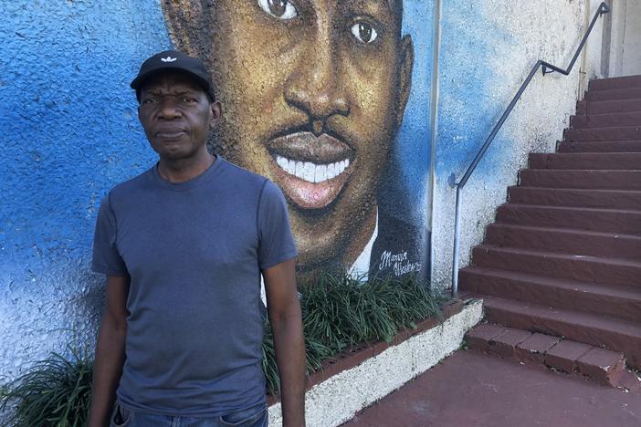 Marvin Weeks in front of his mural of Ahmaud Arbrery.