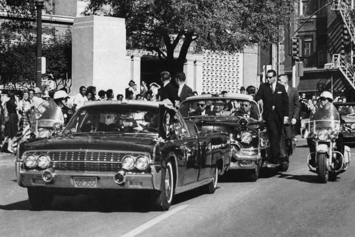 In this Nov. 22, 1963, file photo, seen through the foreground convertible's windshield, President John F. Kennedy's hand reaches toward his head within seconds of being fatally shot. About 90% of the government records surrounding the assassination have been released but the release of the remaining records have now been delayed.