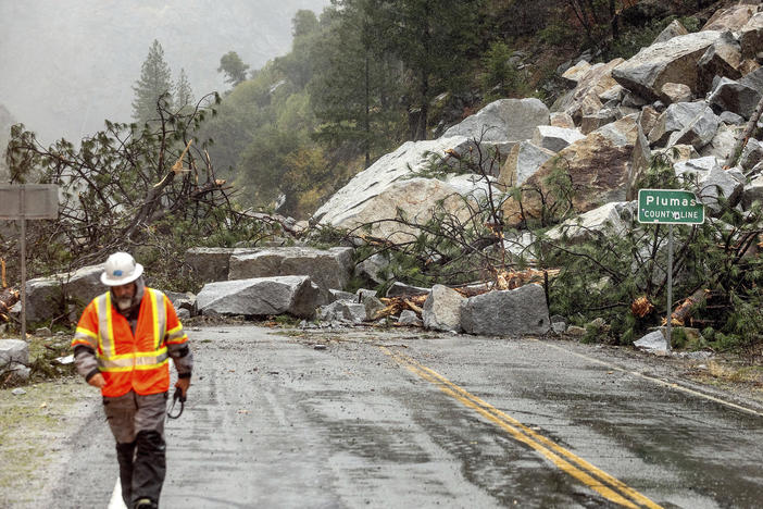 Caltrans maintenance supervisor Matt Martin walks by a landslide covering Highway 70 in the Dixie Fire zone Sunday in Plumas County, Calif. Heavy rains blanketing Northern California created slide and flood hazards in land scorched during last summer's wildfires.