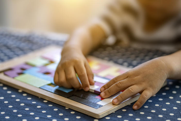 A child plays with colorful plastic blocks. Children in need of quality childcare is in high demand but short supply, including for disabled children,  parents say.