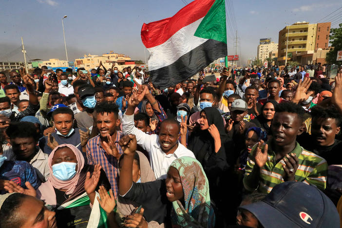 Sudanese protesters lift national flags as they rally on 60th Street in the capital Khartoum, to denounce overnight detentions by the army of government members, on Oct. 25, 2021.