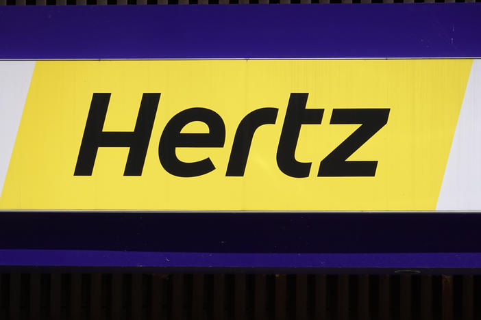 A sign hangs above a Hertz rental car office on Aug. 4, 2020, in Chicago. The company said it's buying 100,000 Teslas in a bold move to diversify into electric vehicles.