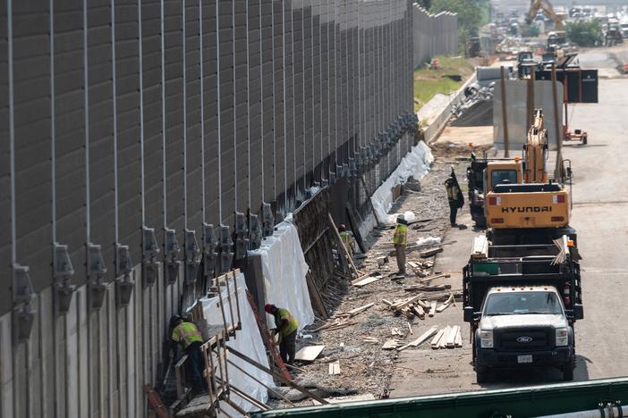 Construction workers build a sound wall along Interstate Highway 66 in Fairfax, Va., this past August. While Congress debates President Biden's infrastructure bill, some rural transportation projects are in limbo.