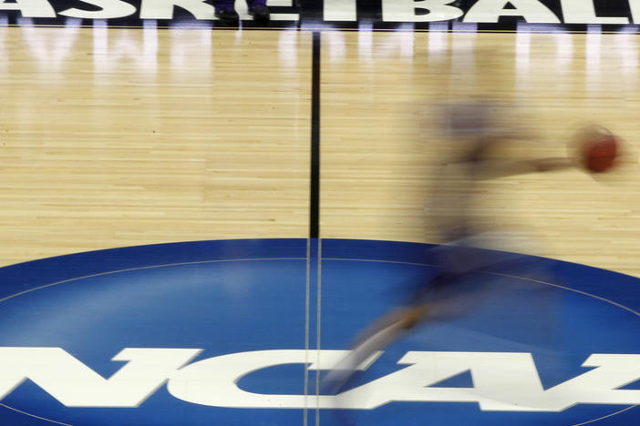 A player streaks across the NCAA logo at midcourt during basketball practice in this file photo from March 14, 2012.