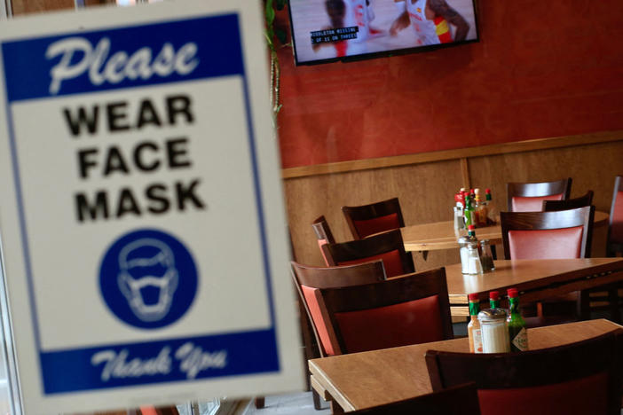 A sign asking patrons to wear a mask is seen at the entrance of a restaurant in New York City on Aug. 3. The spread of the delta variant led to sharply slower economic growth in the July-to-September quarter.