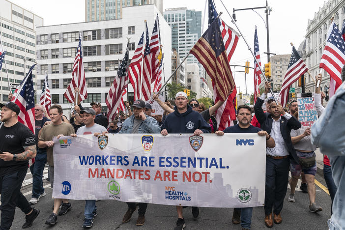 New York city municipal workers, including police officers and firefighters, rally on Monday against a vaccination mandate. City workers are required to get vaccinated against COVID-19 by Nov. 1 or risk losing their jobs.