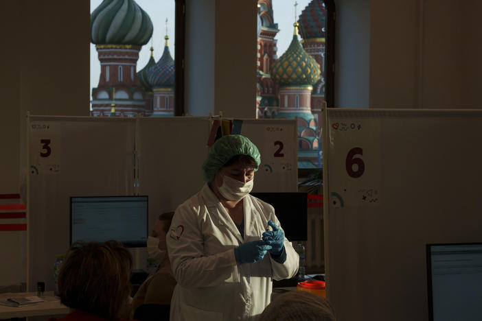 A medical worker prepares a shot of Russia's Sputnik Lite coronavirus vaccine at a vaccination center last week in Moscow's GUM department store in Red Square with the St. Basil Cathedral in the background. The global death toll from COVID-19 has topped 5 million.