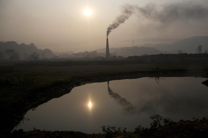 Smoke rises from a brick kiln on the outskirts of Gauhati, India, in 2015. India's pledge this week to reach net zero carbon emissions by 2070 factors into a new, more optimistic, analysis by the International Energy Agency on climate change goals.