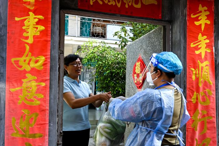 A community worker delivers daily necessities to a household during quarantine conditions in the southwestern Chinese city of Ruili. Residents have taken to social media to complain about what they describe as harsh lockdown measures brought on by China's zero COVID policy.