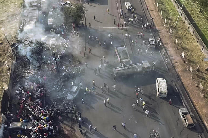 In this photograph issued Saturday by Sierra Leone's National Disaster Management Agency, people gather around the charred oil tanker that exploded after being struck by a truck in the Wellington suburb of Sierra Leone's capital Freetown on Saturday.