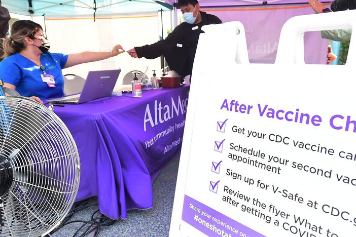 A nurse from AltaMed Health Services hands out the vaccine card to people after receiving their Covid-19 vaccine in Los Angeles, California on August 17, 2021.