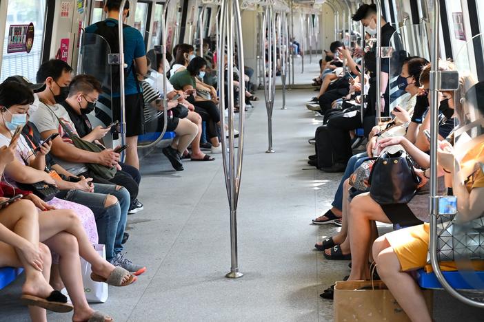 People in Singapore mask up to take a mass rapid transit train on Friday. Singapore has one of the highest vaccination rates in the world. As of Sunday, 85% of its population was fully vaccinated.