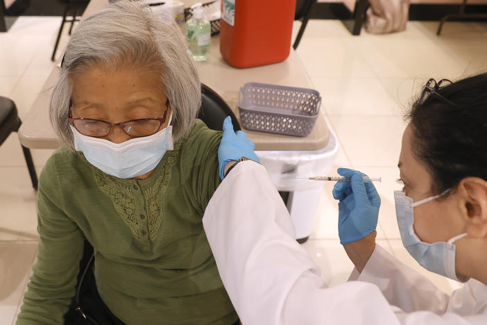 Safeway pharmacist Shahrzad Khoobyari administers a Pfizer-BioNTech COVID-19 booster shot to Chen Knifsend at a vaccination clinic in San Rafael, Calif., in October. The companies are seeking regulatory authorization to expand boosters to everyone 18 and older.