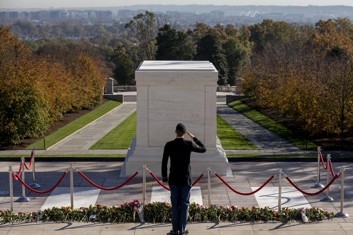 After placing flowers, a person in military uniform salutes at the Tomb of the Unknown Soldier.