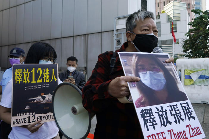 Pro-democracy activists (right) hold placards with the picture of Chinese citizen journalist Zhang Zhan as they march to the Chinese central government's liaison office in Hong Kong in Dec. 2020.