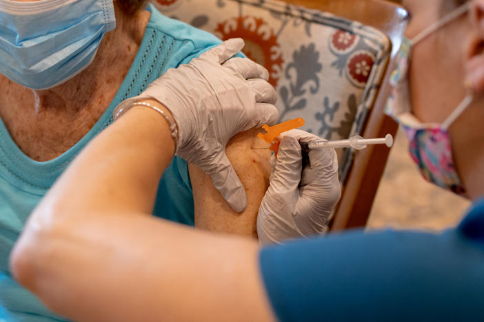 A health care worker administers a third dose of the Pfizer-BioNTech COVID-19 vaccine at a senior living facility in Worcester, Pa., in August.