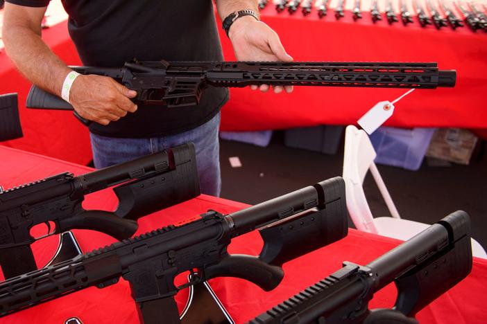 A clerk shows a customer an AR-15 style rifle at a gun show in Costa Mesa, Calif. in June 2021. Gun sales increased in the U.S, following COVID-19 pandemic lockdowns.