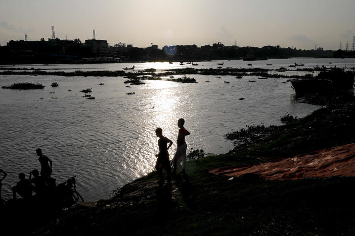 Two boys stand at the edge of the Buriganga River in Dhaka, Bangladesh, in July. A recent study finds that globally, boys and young men made up two-thirds of all deaths among young people in 2019.