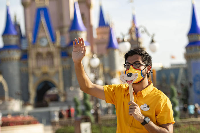 A Disney employee welcomes guests to Walt Disney World Resort on July 11, 2020 in Lake Buena Vista, Fla. Disney has paused its COVID-19 vaccine mandate to comply with a new Florida law.
