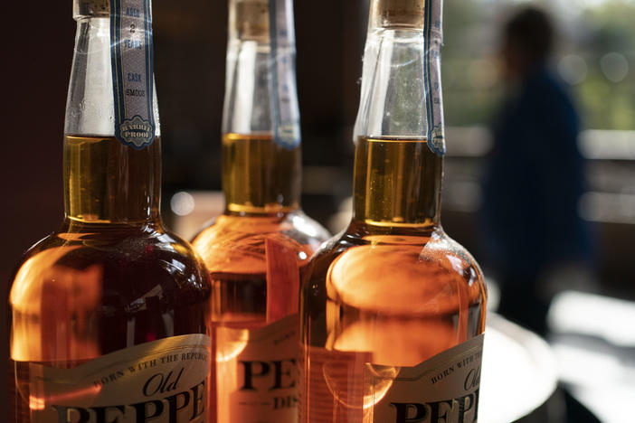 A woman walks past a display of bottles of whiskey at the James E. Pepper Distillery.