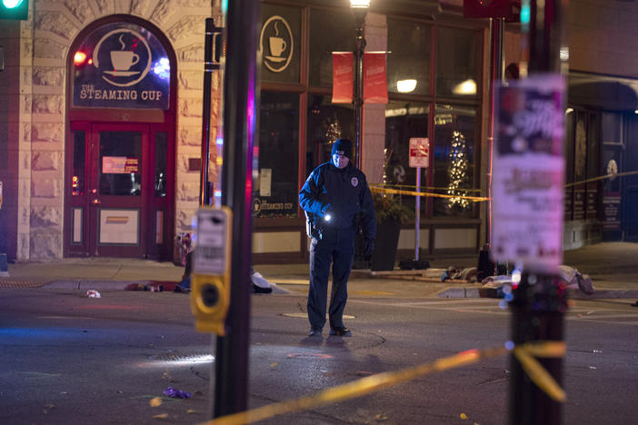 A police officer uses a flashlight while looking for evidence in downtown Waukesha, Wis., after an SUV sped through a barricade and slammed into a Christmas parade, killing and injuring several people on Sunday.