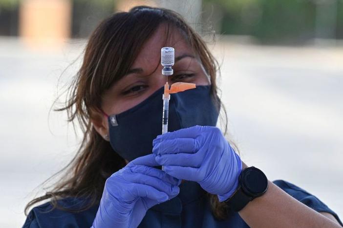 Booster shots are authorized for all U.S. adults, but some are wondering if they need them. A nurse fills a syringe with a Pfizer-BioNTech dose at a pop-up vaccine clinic in the Arleta neighborhood of Los Angeles.