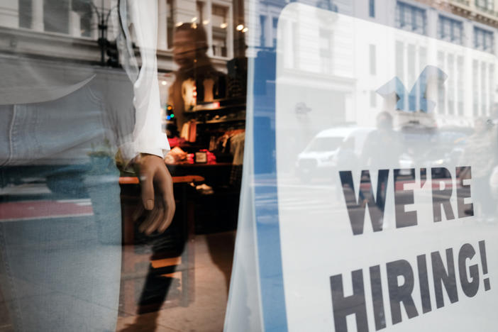 People walk by a hiring sign in a store window in New York on Nov. 17.