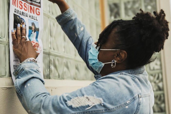 A community member posts flyers for Amaria Hall.