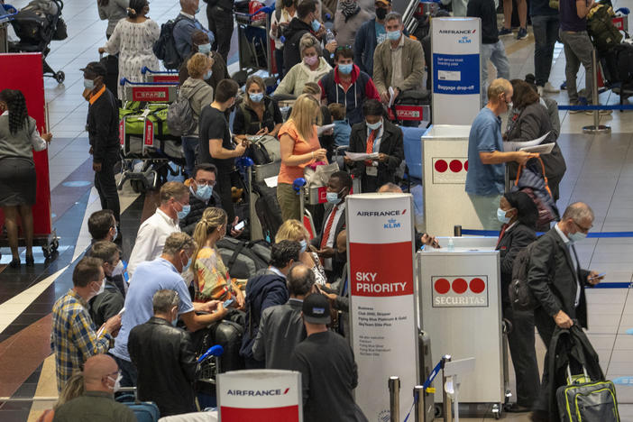 People line up to get on the Air France flight to Paris at OR Tambo's airport in Johannesburg, South Africa, on Friday. The United States, Israel and other European nations have already imposed travel restrictions on South Africa and other nations in the region.