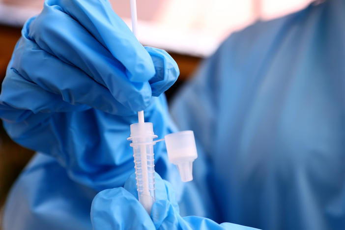 A registered nurse stirs a nasal swab in testing solution after administering a COVID-19 test  in Los Angeles, Calif. Increased testing could help in efforts to detect and track new variants like omicron.