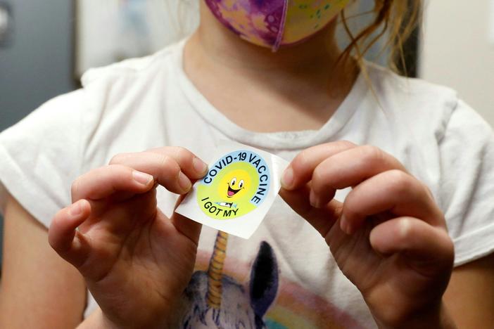 A 6 year-old child holds a sticker she received after getting the Pfizer-BioNTech COVID-19 vaccine at the Child Health Associates office in Novi, Mich., on Nov. 3.